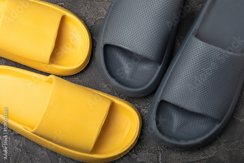 A pair of stylish rubber slippers on a black marble background.Changeable shoes.Beach shoes.Copy space. Place for text.