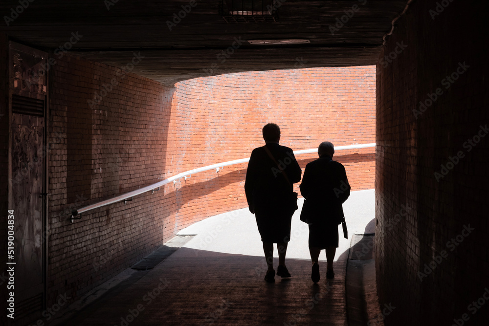 Two elderly ladies backlit in a passageway