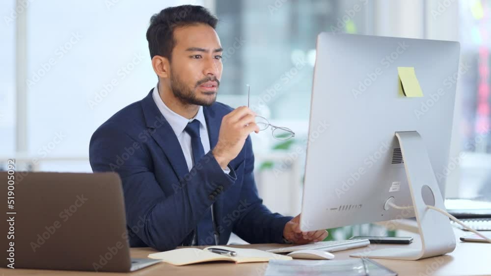 Information Technology software engineer analyzing data management system. Thoughtful analyst looking for a solution. Thinking IT manager working on a desktop computer and laptop in a modern office.