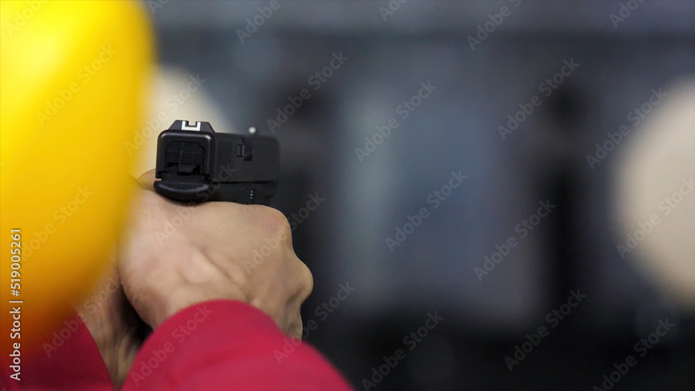 Back view of man shoots a gun at shooting range close up. Man fires