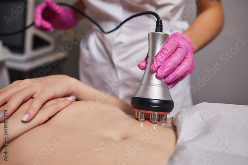 Rf skin tightening, belly. Hand of cosmetician, female body. Non surgical body sculpting.