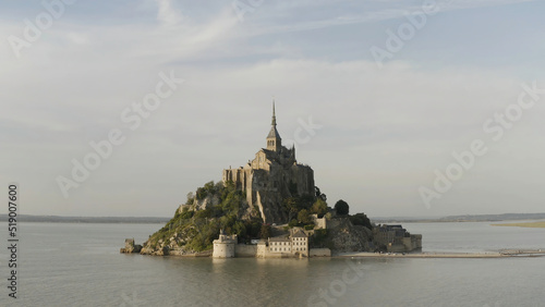 Aerial panoramic view of unique temple on the island surrounded by the sea on blue cloudy sky background. Action. Amazing Mont-Saint-Michel castle, France.