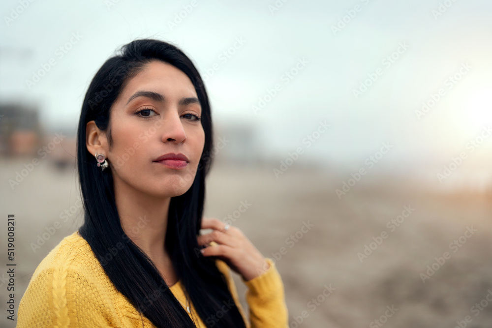 portrait of a young latin woman on the beach looking at the camera with confidence unfocused background portrait of a young latin woman on the beach looking at the camera with confidence unfocused background