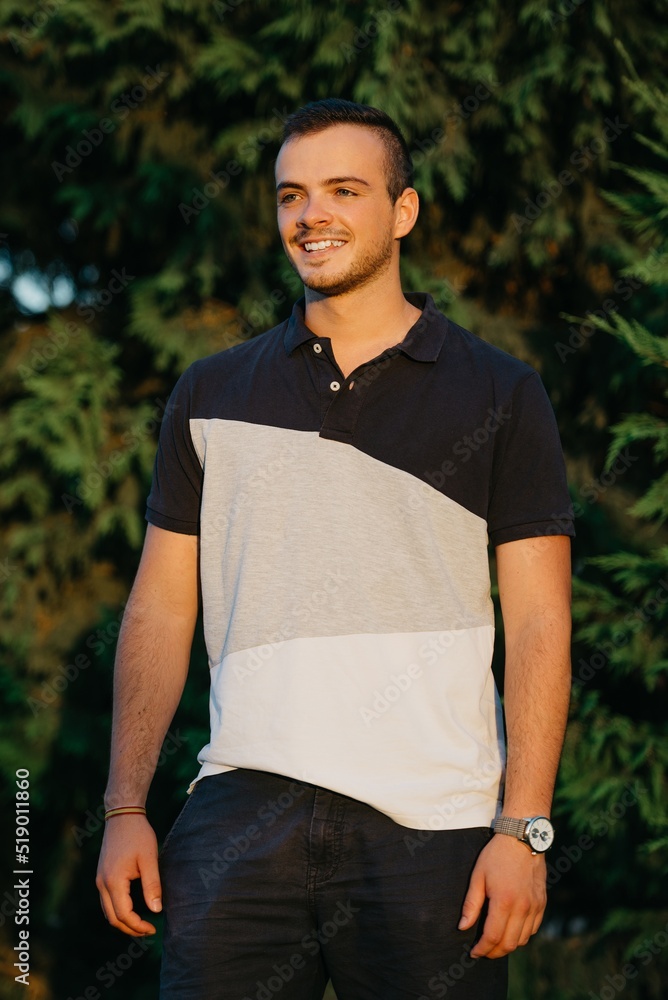 A smiling guy is having fun with green bushes in the background at the sunset in Valencia.