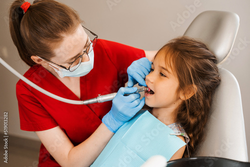 Child dentist makes professional teeth cleaning in dentistry. Professional hygiene for teeth of child in dentistry. Pediatric dentist examines and consults kid patient in dentistry.