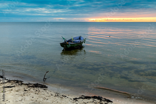 Lonely fishing boat on sandy beach of the Baltic Sea at dawn