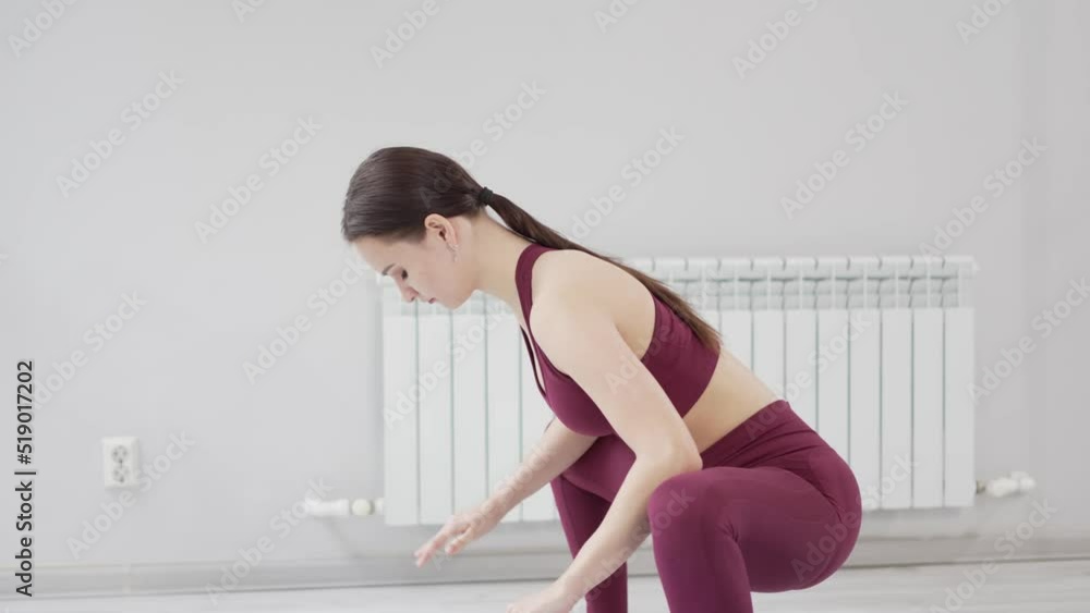warm-up and stretching. beautiful woman in burgundy tracksuit exercises in gym. warm-up and stretching. beautiful woman in burgundy tracksuit exercises in gym.