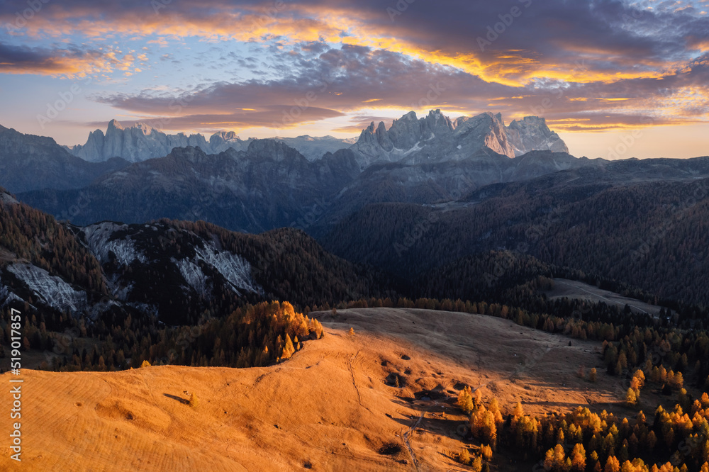 Incredible autumn view at Valfreda valley in Italian Dolomite Alps. Yellow grass, orange larches forest and snowy mountains peaks on background. Dolomites, Italy. Landscape photography