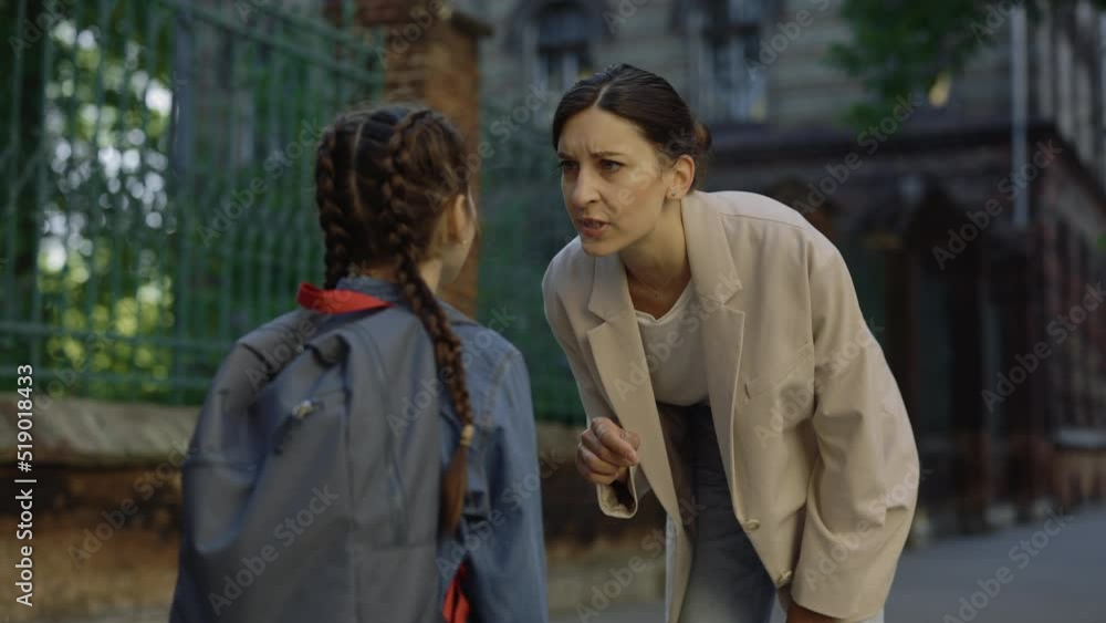 Female teacher standing with schoolgirl giving recommendations and pointing finger on child. Woman abuse little girl outside. Abuse relations Female teacher standing with schoolgirl giving recommendations and pointing finger on child. Woman abuse little girl outside. Abuse relations