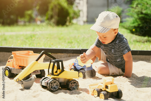 Child playing in sandbox. Little boy having fun on playground in sandpit. Outdoor creative activities for kids. Summer and childhood concept photo
