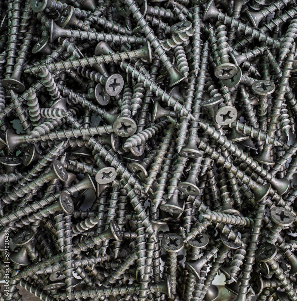 the background consists of a pile of black screws. the concept of construction and repair the background consists of a pile of black screws. the concept of construction and repair