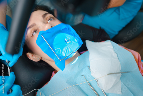 Closeup portrait of a female patient with a cofferdam system in a modern dental office. Dental equipment photo