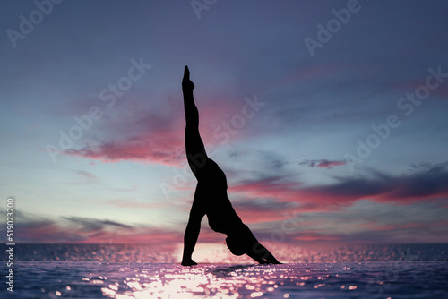 Woman doing yoga on the beach during the sunset. Urdhva Prasarita Eka Padasana photo