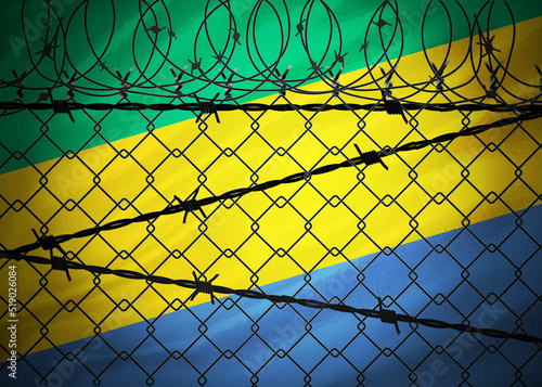 Gabon flag behind barbed wire and metal fence