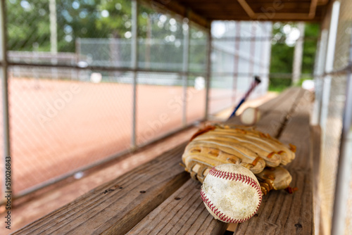 Baseball with glove on dugout bench with blurred background