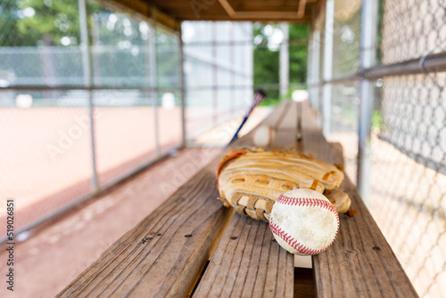 Baseball with glove on dugout bench with blurred background