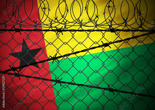 Guinea Bissau flag behind barbed wire and metal fence