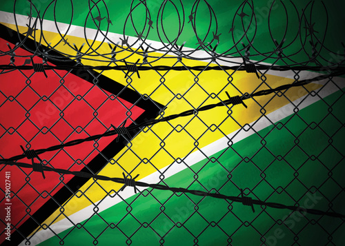 Guyana flag behind barbed wire and metal fence