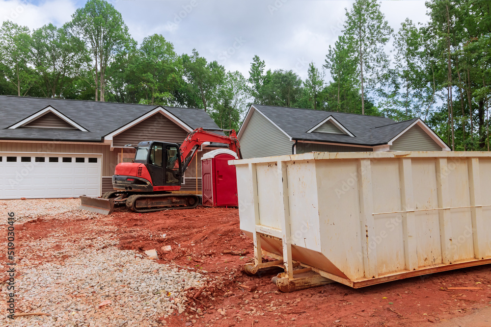 There is an industrial dumpster rubbish removal container under the building on the property in construction site