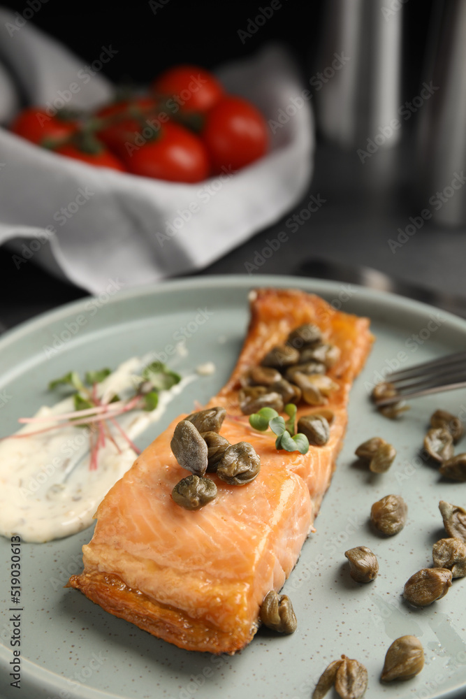 Delicious salmon with capers and sauce on plate, closeup