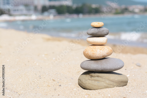 Stack of stones on sandy beach near sea, space for text