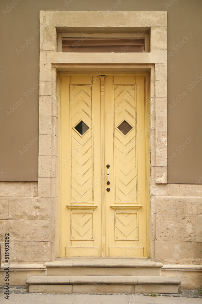 View of building with yellow wooden door. Exterior design View of building with yellow wooden door. Exterior design