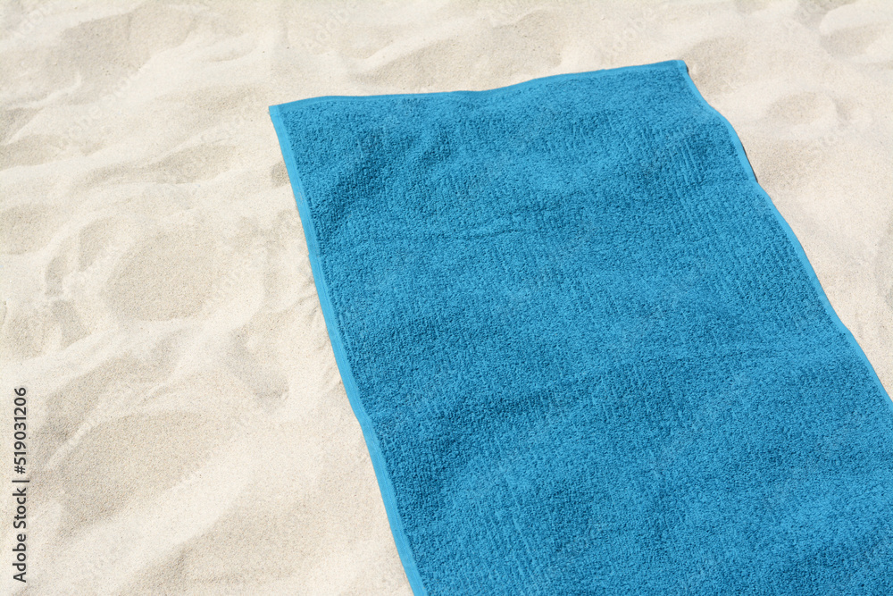 Beautiful soft blue towel on sandy beach