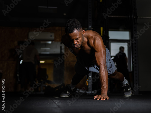 African american man doing one arm push ups in the gym. 