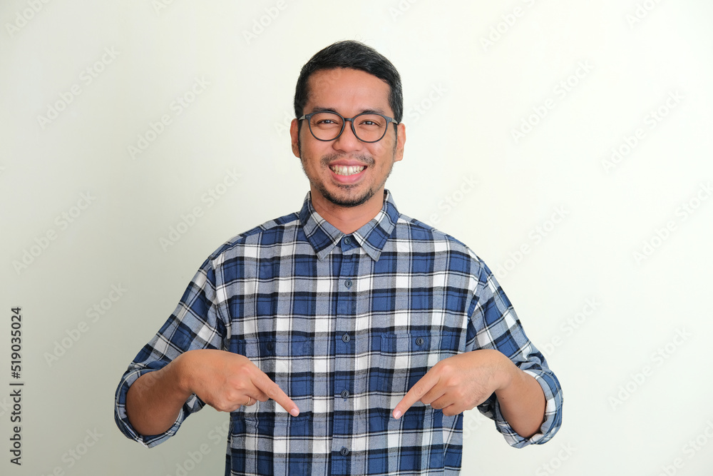 Adult Asian man smiling happy while pointing down Adult Asian man smiling happy while pointing down