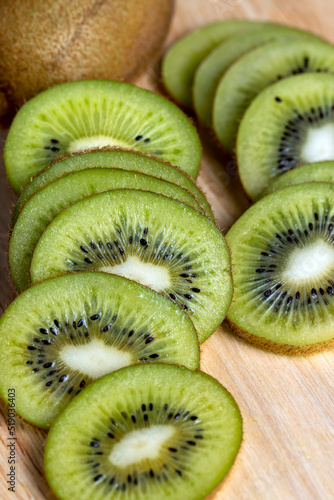 sliced green kiwi fruit on a wooden board
