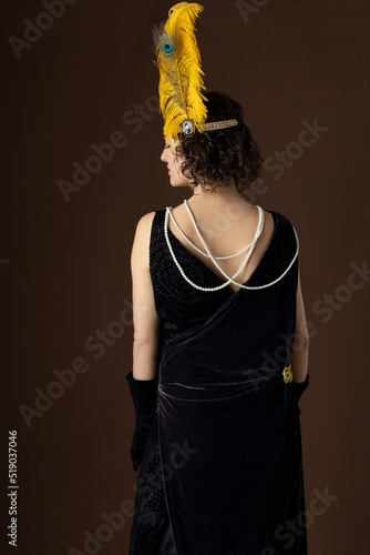 1920s woman wearing an evening gown and a head band with a large feather