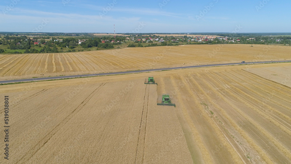 Combine harvester at work harvesting field wheat. Aerial view Combine harvester mows ripe spikelets, barley, rye. Combine harvester harvest ripe wheat on a farm. Combine harvester at work harvesting field wheat. Aerial view Combine harvester mows ripe spikelets, barley, rye. Combine harvester harvest ripe wheat on a farm.