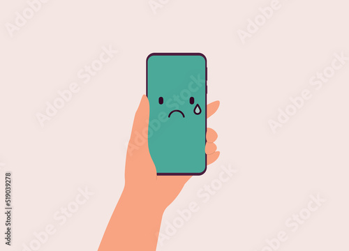 One Human's Hand Holding Mobile Phone With Sad Face Emoji On Green Screen. Close-Up. Flat Design Style, Character, Cartoon.