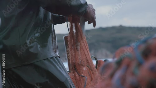 A local fisherman seen seperating fishes caıught on his net on a small fishing boat.  photo