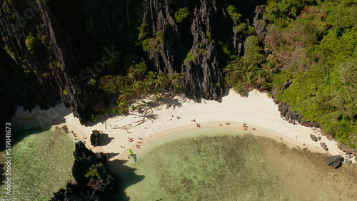 Bay with beach and clear blue water surrounded by cliffs, aerial view. El nido, Philippines, Palawan. tropical beach with palm trees. Seascape with tropical rocky islands, ocean blue water. Summer and