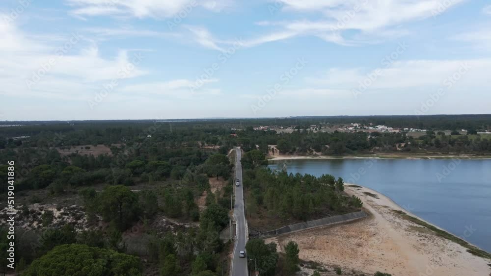 Drone reveal shot with a tilt up movement following a car going by a straight road, next to a lake Drone reveal shot with a tilt up movement following a car going by a straight road, next to a lake