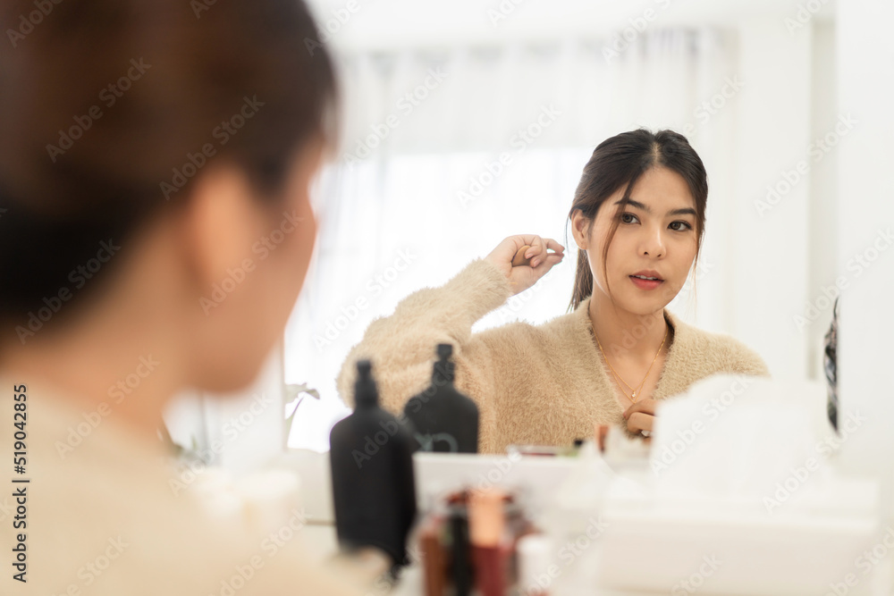Smiling of young beautiful pretty asian woman clean fresh healthy white skin looking at mirror.asian girl touching on her face with hand and applying cream at home.spa and beauty concept.