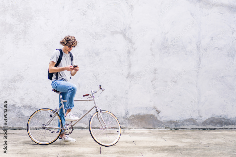 Fototapeta premium Portrait of casual hipster handsome businessman with backpack looking on smartphone while commuting riding bicycle on the street city way go to work.business travel transport bike concept