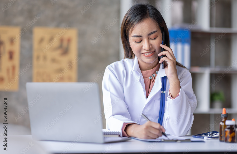 Young Asia Female doctor talking on a cellphone in a modern office Young Asia Female doctor talking on a cellphone in a modern office