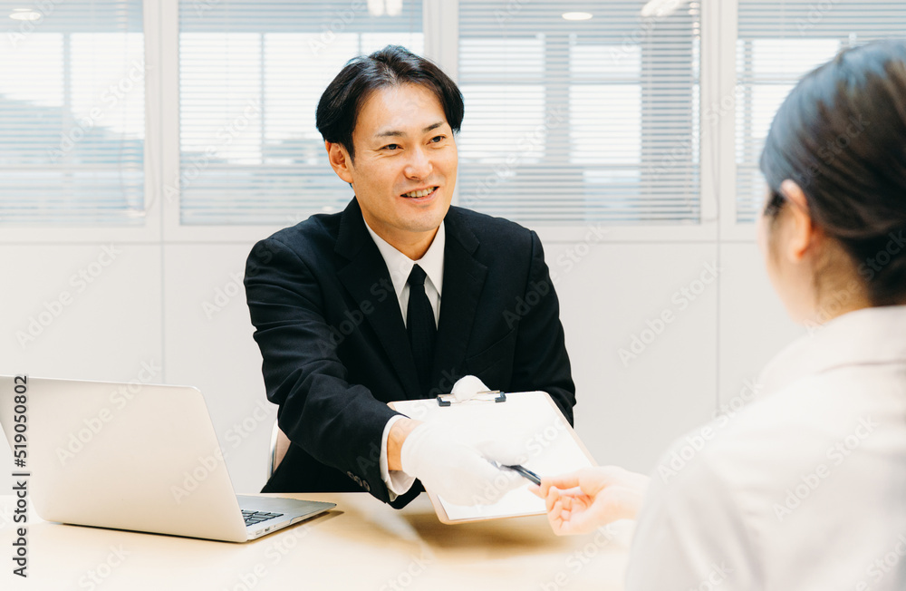 Fotografie 契約書にサインを求める白手袋をつけたビジネスマン（鑑定士・質屋・男性）