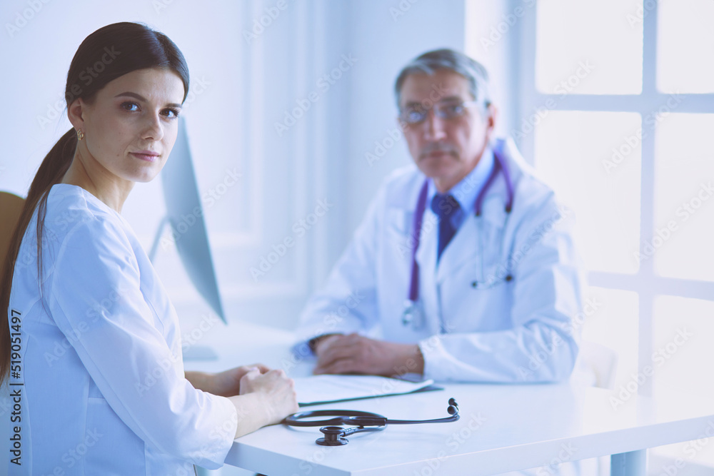 Two doctors smiling in consulting room in hospital Two doctors smiling in consulting room in hospital
