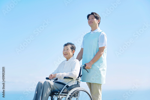 屋外で高齢者女性が乗る車椅子を押す介護士 © siro46