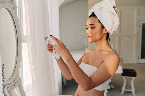 Young beautiful asian woman making face mask in the bathroom in front of the mirror.