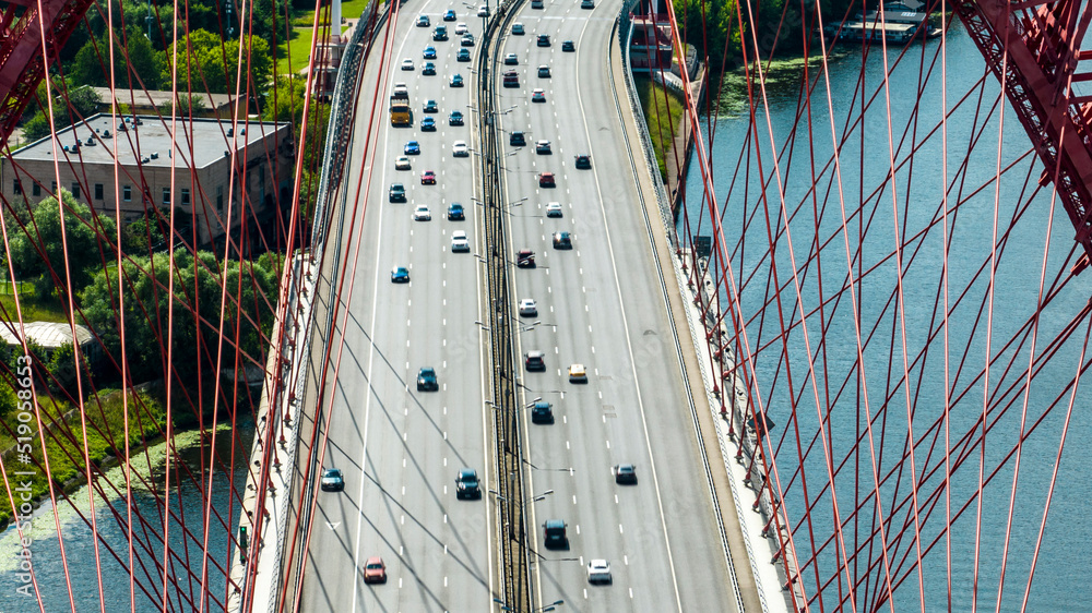 Obraz premium panoramic view of the red bridge over the river on the freeway on a sunny day taken from a drone