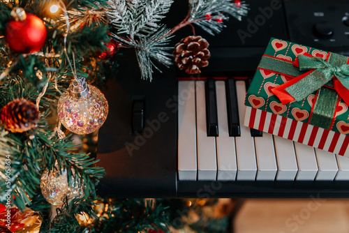 Photography a Christmas gift on piano keys and a decorated Christmas tree with lights