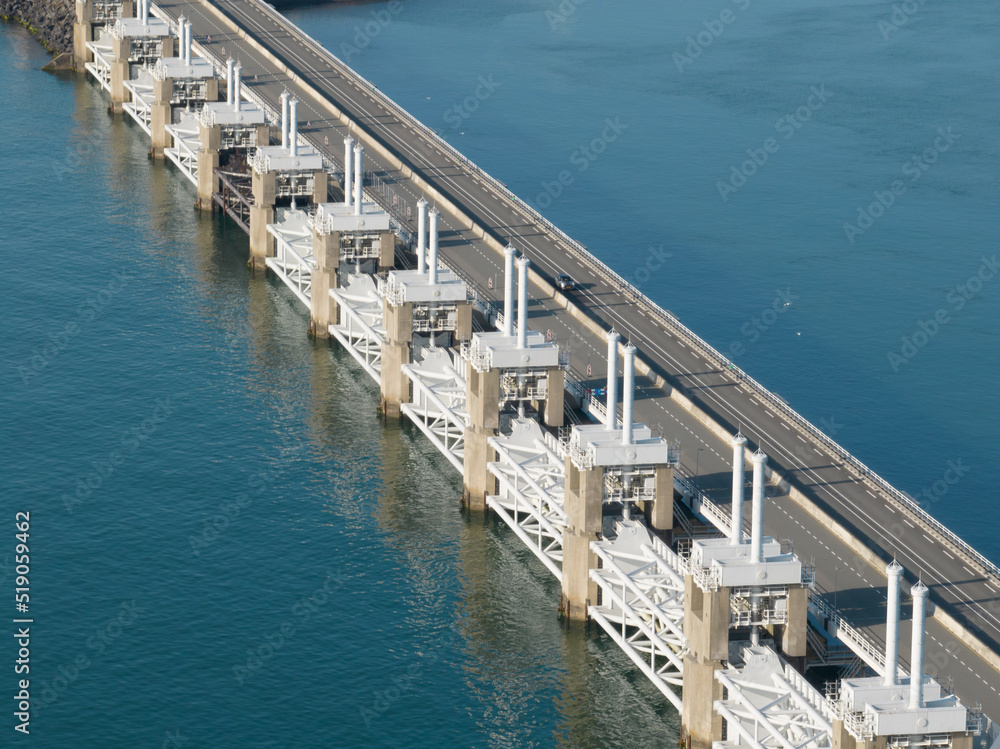 The Oosterscheldekering is a flood defense system in the Netherlands, part of the Delta Works, in the provinces of Zeeland. Engineering barrages overview on a calm sea. Aerial overhead view.