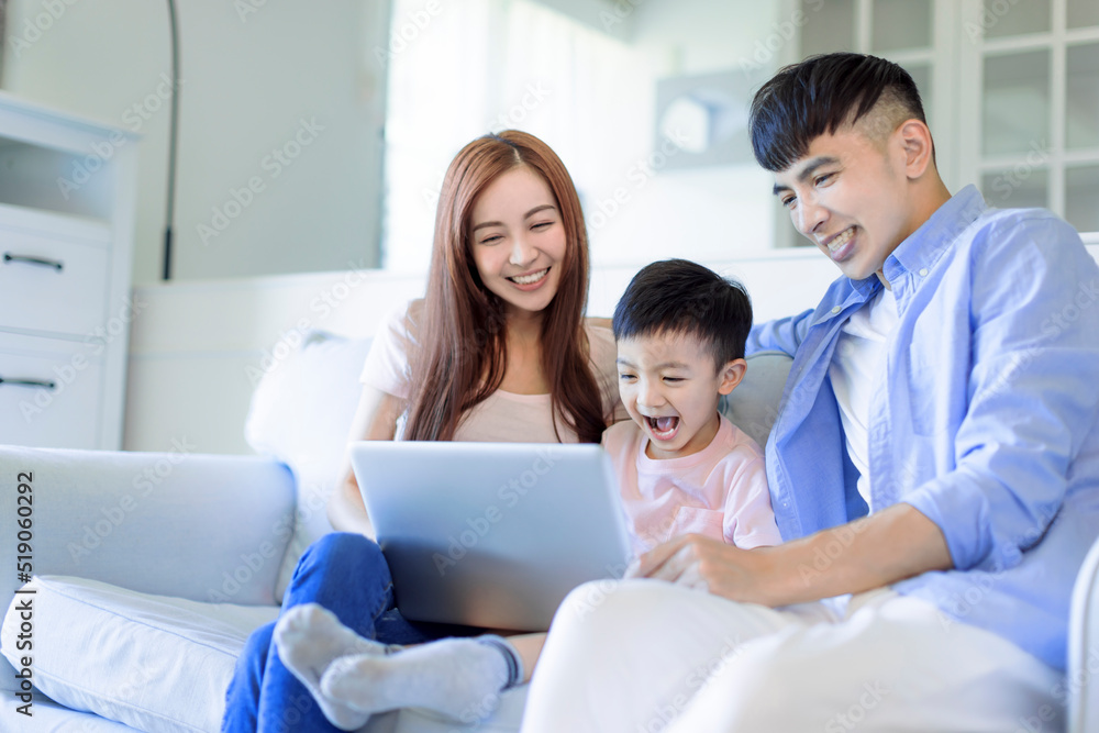 young happy cheerful family resting on sofa in living room watching the laptop young happy cheerful family resting on sofa in living room watching the laptop