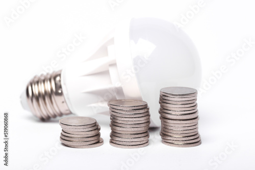 Saving money concept. Energy saving led light bulb with a stack of coins on white background
