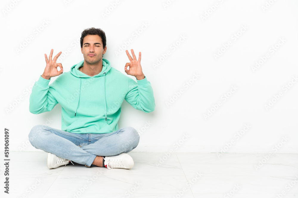 Caucasian handsome man sitting on the floor in zen pose