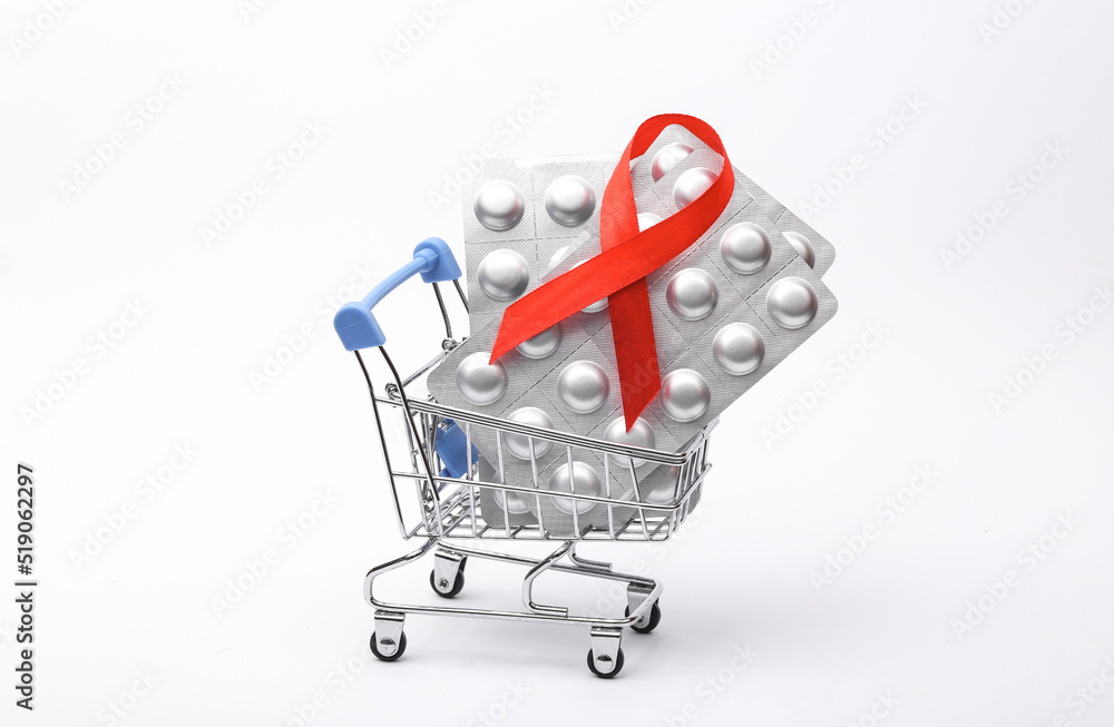 Shopping trolley and Blister pills with red ribbon symbol of the fight against AIDS on white background